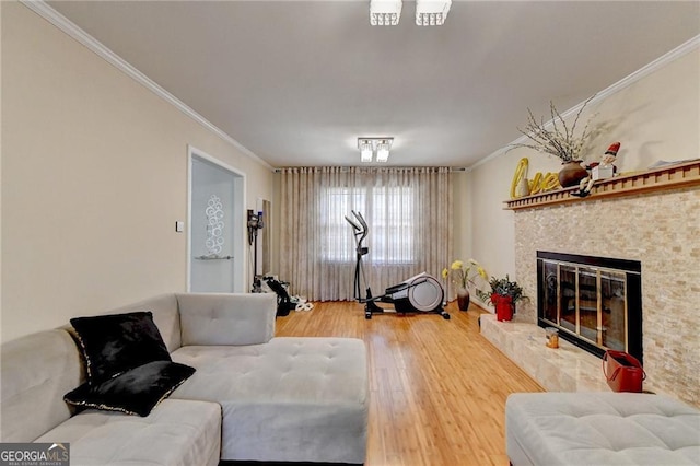 living area featuring a glass covered fireplace, wood finished floors, and crown molding