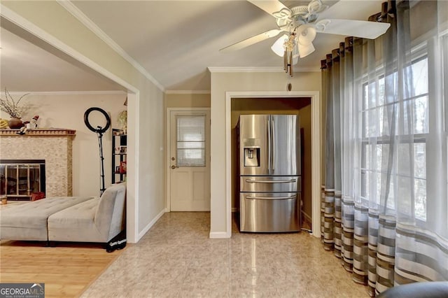 interior space with plenty of natural light, ornamental molding, a tiled fireplace, and stainless steel fridge with ice dispenser