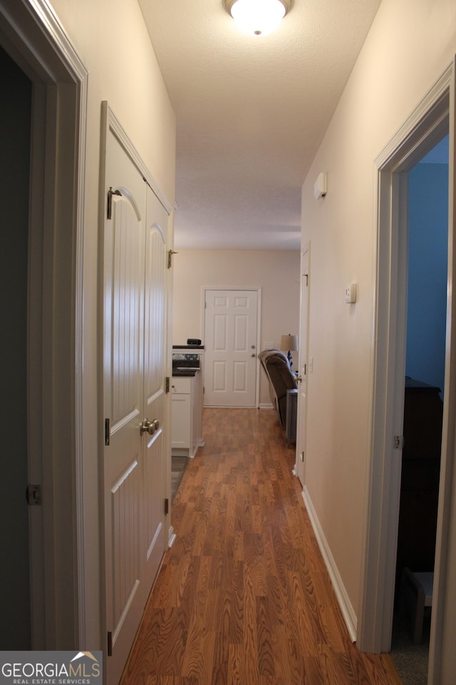 corridor featuring dark wood finished floors and baseboards