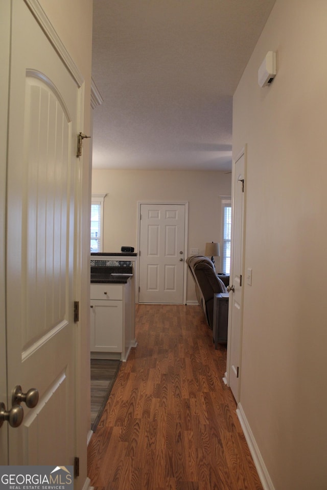 hallway featuring dark wood-style flooring and baseboards