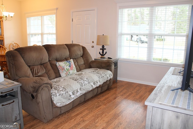 living room with baseboards, wood finished floors, a wealth of natural light, and an inviting chandelier