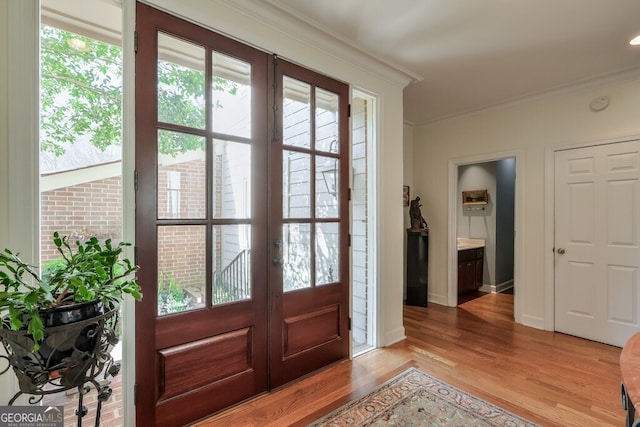 interior space featuring light wood-style flooring, ornamental molding, baseboards, and french doors