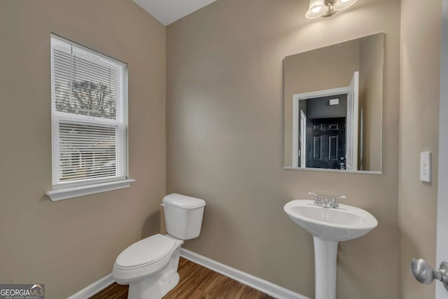 half bath with wood finished floors, toilet, and baseboards