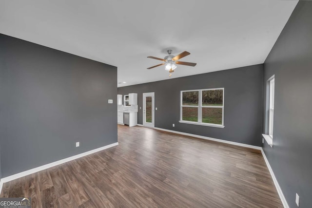 unfurnished living room with dark wood-style floors, ceiling fan, and baseboards