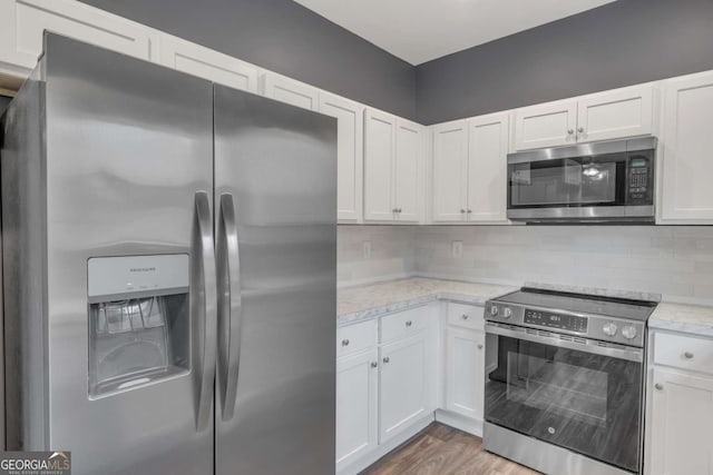 kitchen with stainless steel appliances, white cabinetry, and decorative backsplash