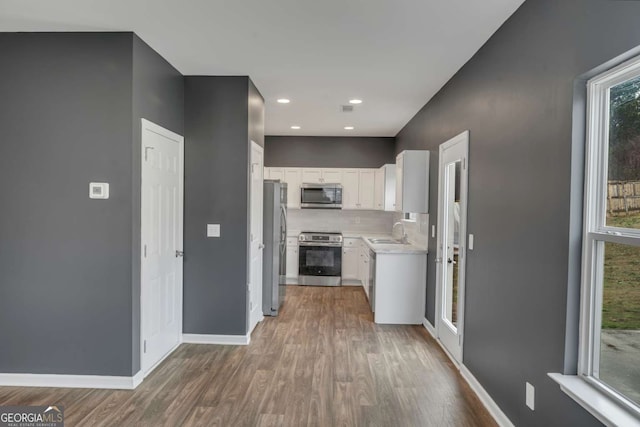 kitchen with baseboards, white cabinets, appliances with stainless steel finishes, light countertops, and a sink