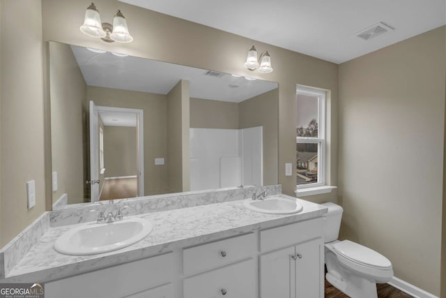 full bath featuring visible vents, a sink, toilet, and double vanity