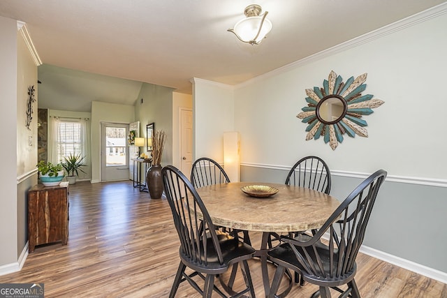 dining space with baseboards, crown molding, and light wood finished floors