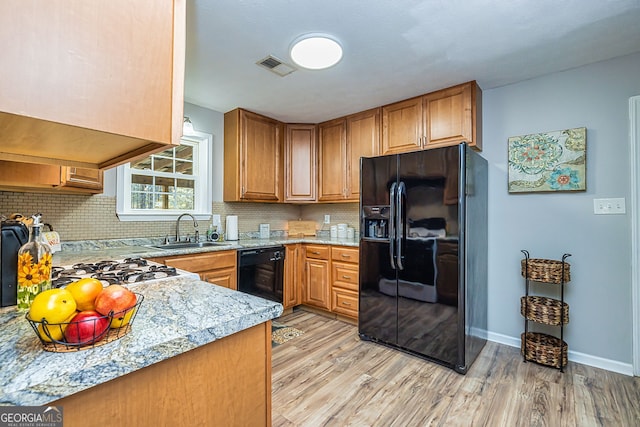 kitchen featuring light wood-style flooring, a sink, visible vents, decorative backsplash, and black appliances