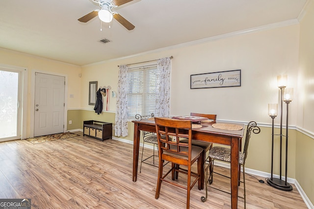 dining space with visible vents, light wood-style flooring, ornamental molding, a ceiling fan, and baseboards