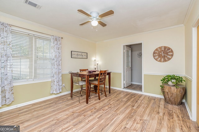 dining area featuring wood finished floors, a ceiling fan, visible vents, baseboards, and ornamental molding