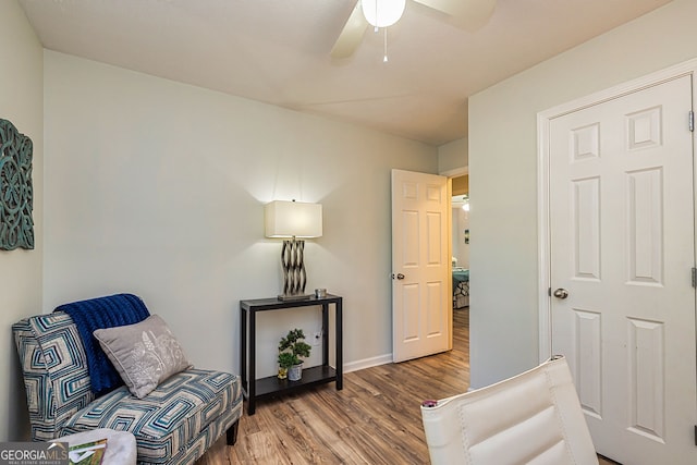 living area featuring baseboards, a ceiling fan, and wood finished floors