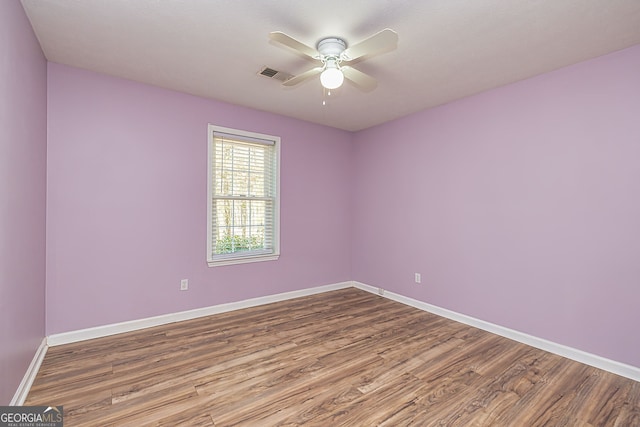 unfurnished room with a ceiling fan, wood finished floors, visible vents, and baseboards