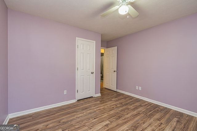 unfurnished bedroom featuring ceiling fan, a closet, wood finished floors, and baseboards