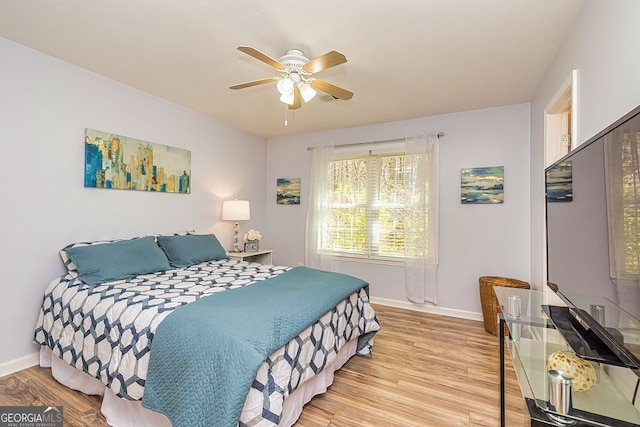 bedroom with light wood-style flooring, baseboards, and a ceiling fan