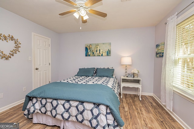 bedroom with a ceiling fan, baseboards, and wood finished floors