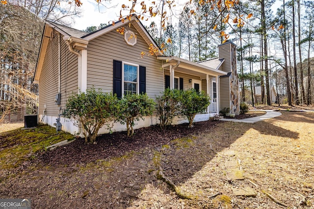 view of side of home with a chimney and cooling unit