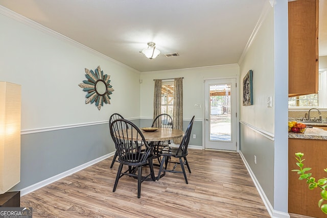 dining room with baseboards, visible vents, ornamental molding, and wood finished floors