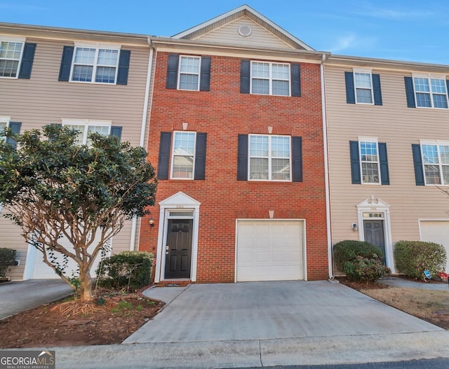 multi unit property with concrete driveway, brick siding, and an attached garage