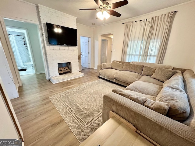 living area with baseboards, ceiling fan, wood finished floors, crown molding, and a fireplace