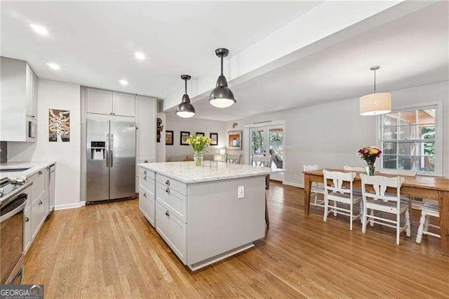 kitchen with pendant lighting, light wood-style flooring, white cabinets, stainless steel built in refrigerator, and range