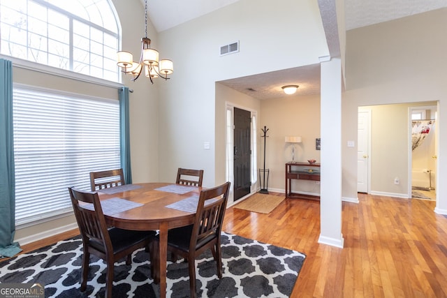 dining space featuring high vaulted ceiling, light wood finished floors, visible vents, and baseboards