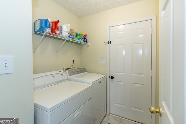 laundry area with laundry area, washing machine and dryer, marble finish floor, and a textured ceiling