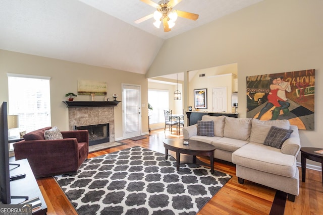 living area featuring ceiling fan, a tile fireplace, wood finished floors, and visible vents