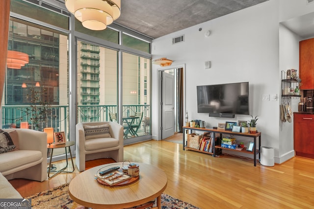 living room featuring plenty of natural light, wood finished floors, visible vents, and floor to ceiling windows