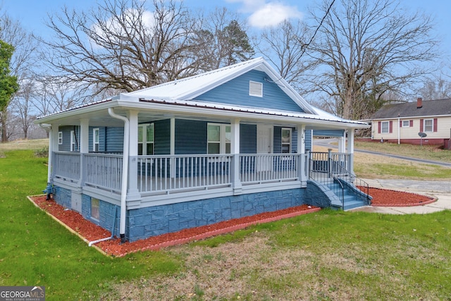 view of front of property with covered porch, a front lawn, and metal roof