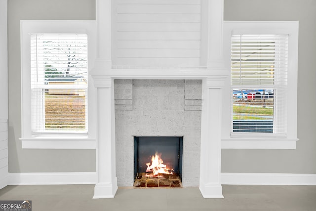 details featuring a warm lit fireplace and baseboards