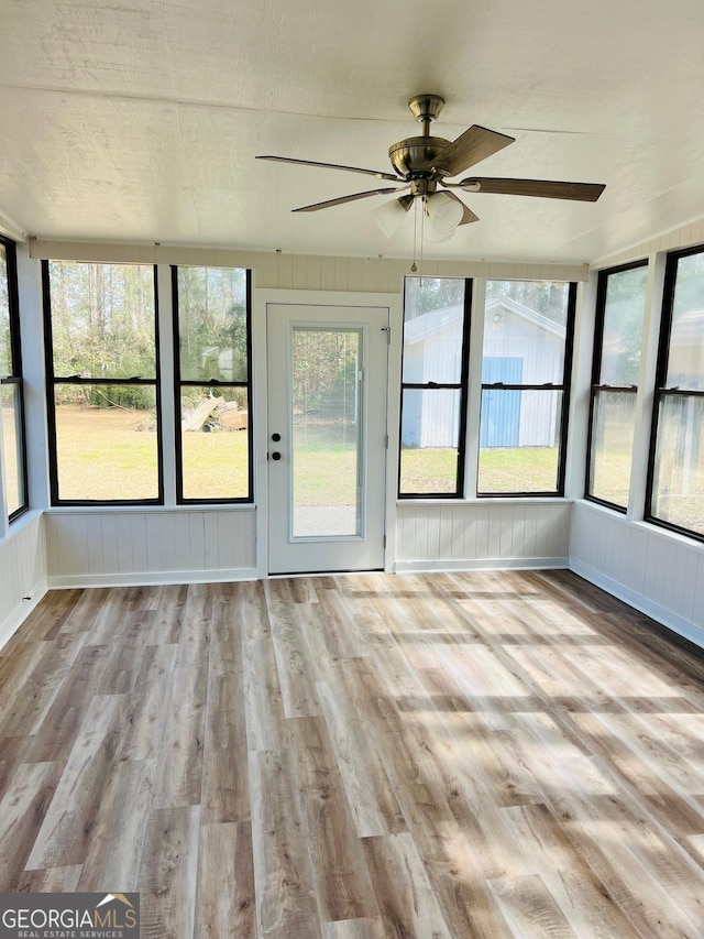 unfurnished sunroom featuring a wealth of natural light and a ceiling fan