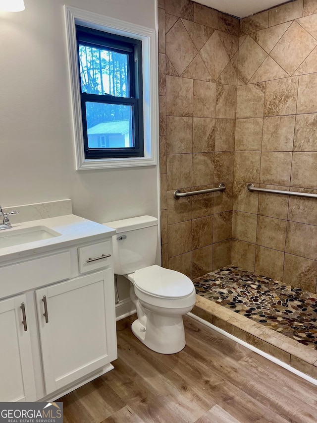 bathroom with toilet, a shower stall, wood finished floors, and vanity