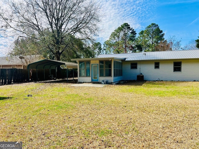 back of property featuring a carport, a sunroom, brick siding, and a lawn