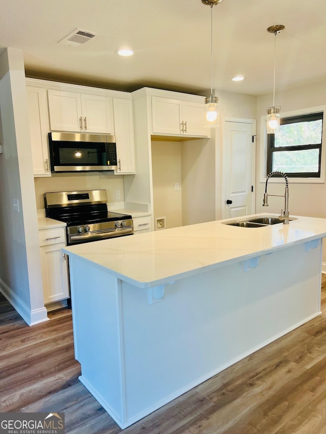 kitchen with stainless steel appliances, white cabinets, a sink, and hanging light fixtures