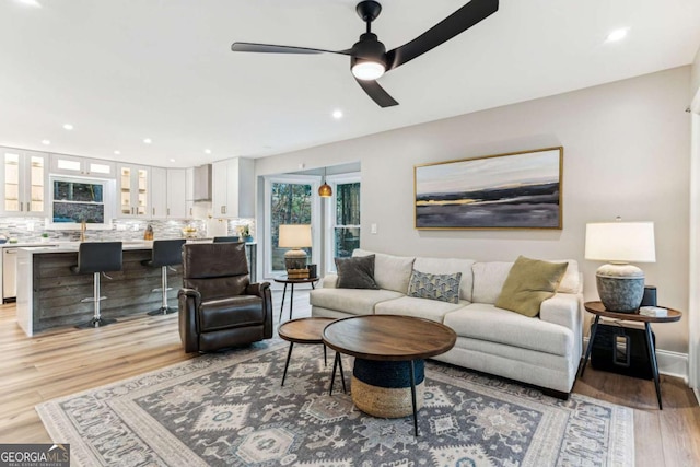 living area featuring light wood finished floors, ceiling fan, and recessed lighting