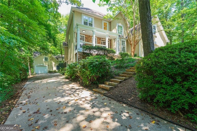 view of front of house featuring stairway, driveway, stucco siding, stone siding, and a garage