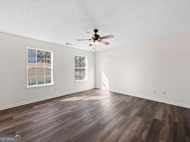 unfurnished room featuring baseboards, visible vents, dark wood finished floors, and a textured ceiling