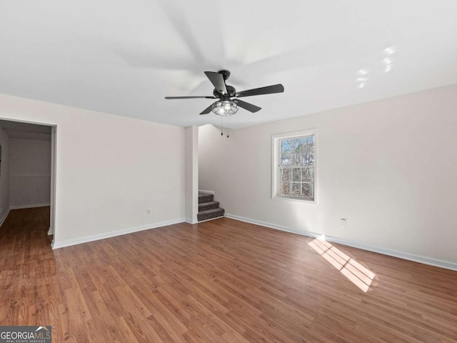 unfurnished living room featuring dark wood-type flooring, baseboards, and stairs