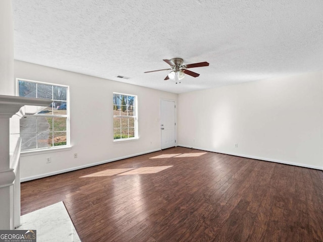 unfurnished living room featuring a textured ceiling, visible vents, baseboards, a ceiling fan, and dark wood-style floors