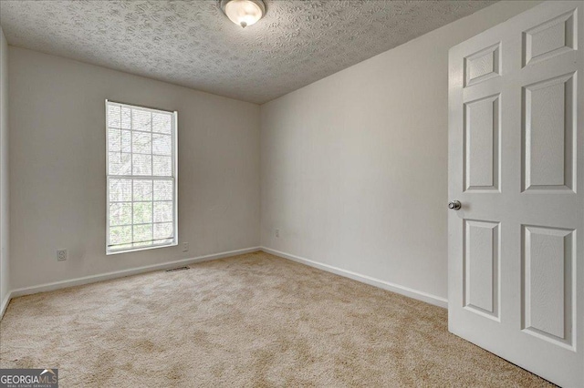 unfurnished room featuring baseboards, visible vents, a textured ceiling, and light colored carpet