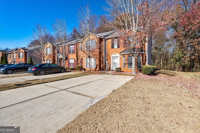 townhome / multi-family property with brick siding, a front yard, and a residential view