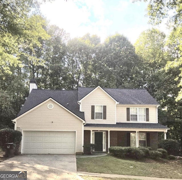 traditional home with driveway, a porch, a chimney, and an attached garage