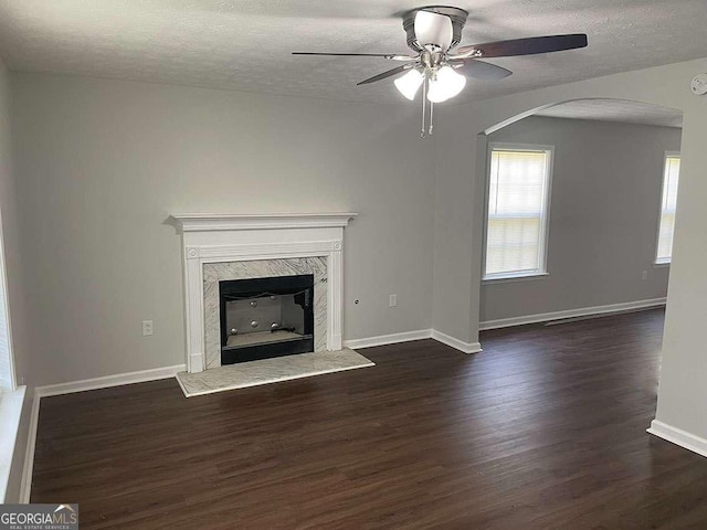 unfurnished living room with dark wood-style floors, plenty of natural light, and a high end fireplace