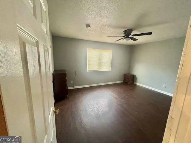 unfurnished bedroom featuring dark wood-type flooring, ceiling fan, a textured ceiling, and baseboards