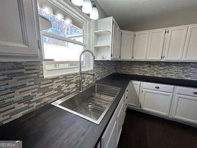 kitchen with open shelves, dark countertops, a sink, and white cabinets