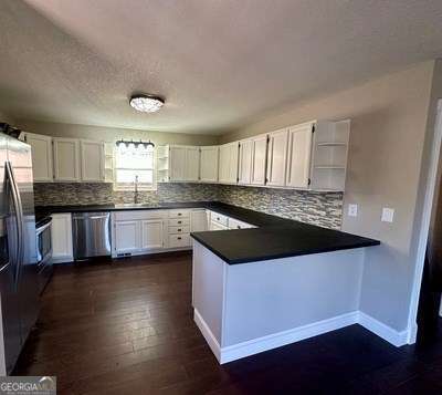 kitchen featuring open shelves, stainless steel appliances, a peninsula, and white cabinets