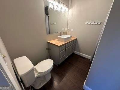 bathroom with toilet, baseboards, wood finished floors, and vanity