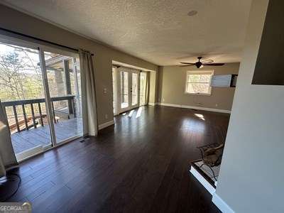 interior space with baseboards, dark wood finished floors, a ceiling fan, a textured ceiling, and french doors