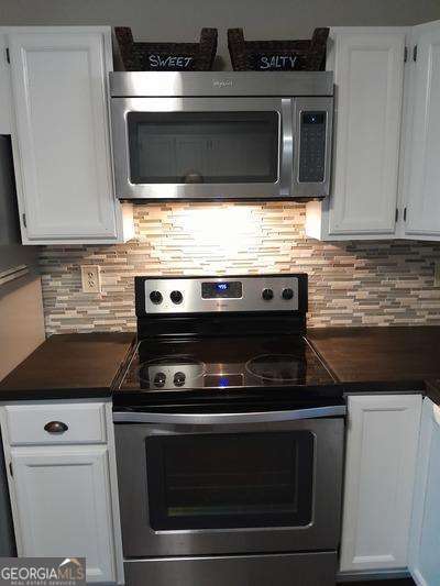 kitchen featuring dark countertops, tasteful backsplash, appliances with stainless steel finishes, and white cabinets